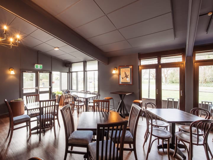 Pub dining room with dark walls, timber chairs and natural light from large windows