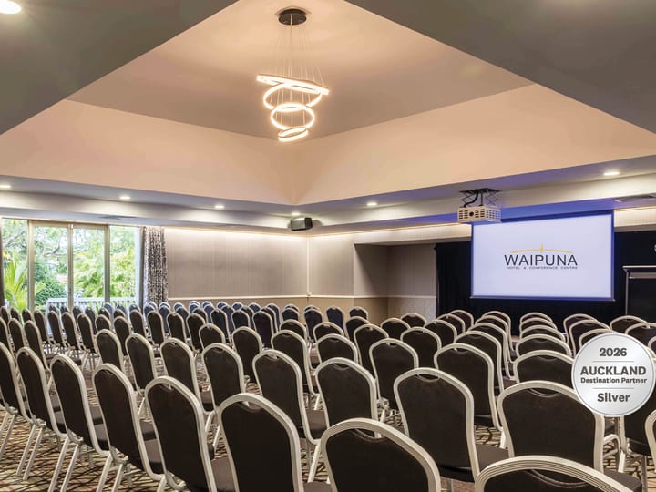 Conference room with theatre-style seating, projection screen, and ring pendant light