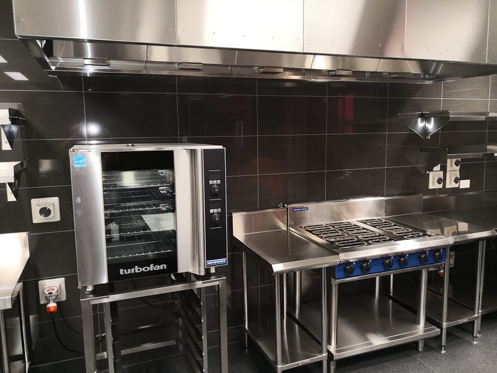 Commercial kitchen with stainless appliances, oven and range hood