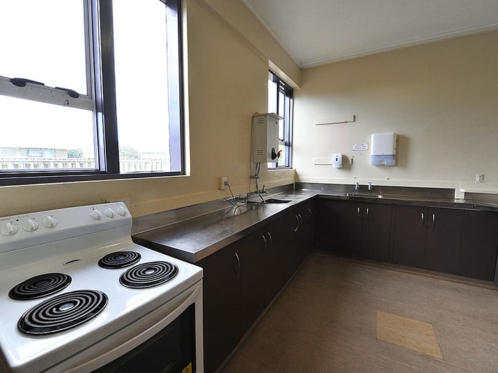 Community kitchen with dark lower cabinets, electric stove, and stainless bench