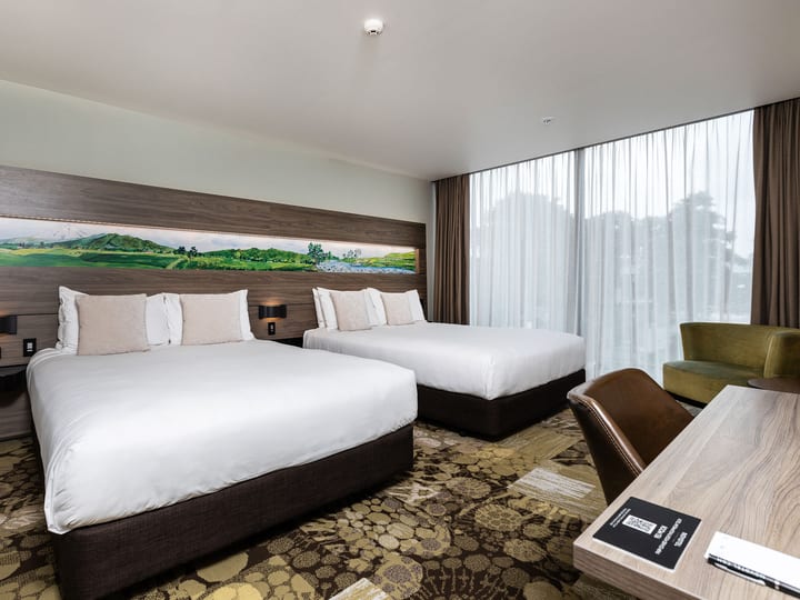 Twin bed hotel room with patterned carpet and artwork above the headboard