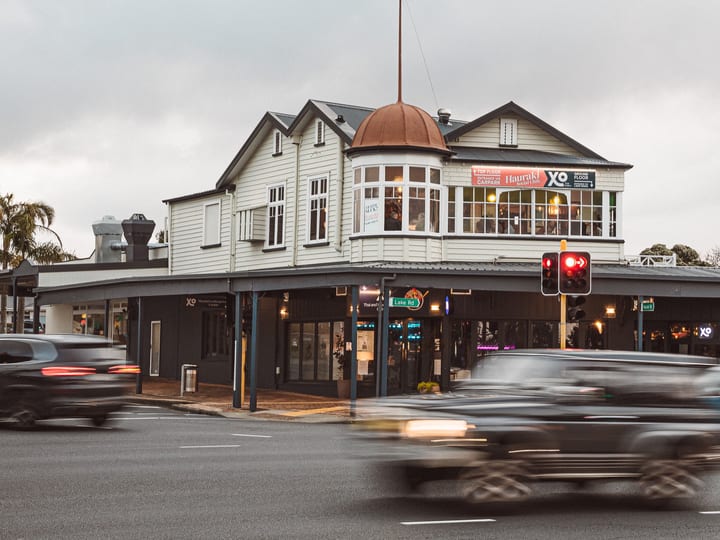 Historic two-storey white timber building on a street corner with copper dome detail