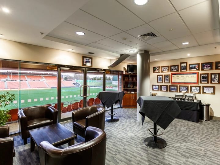 Lounge with leather armchairs, framed sports photos and pitch view