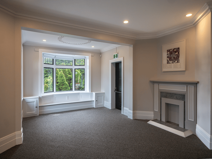 Room with fireplace, bay window and garden view, carpeted floor