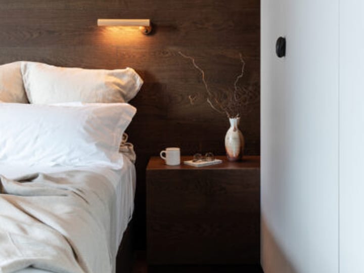 Hotel room with timber-panelled headboard wall and bedside table with harbour view