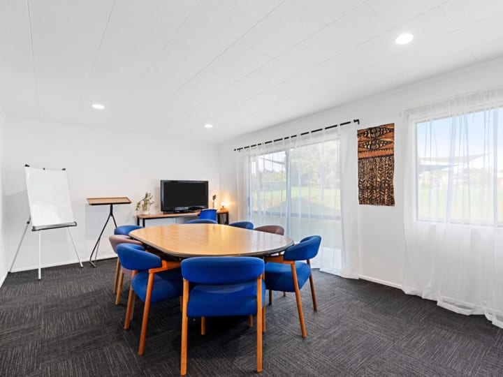 Meeting room with oval table, blue chairs, whiteboard, and large windows