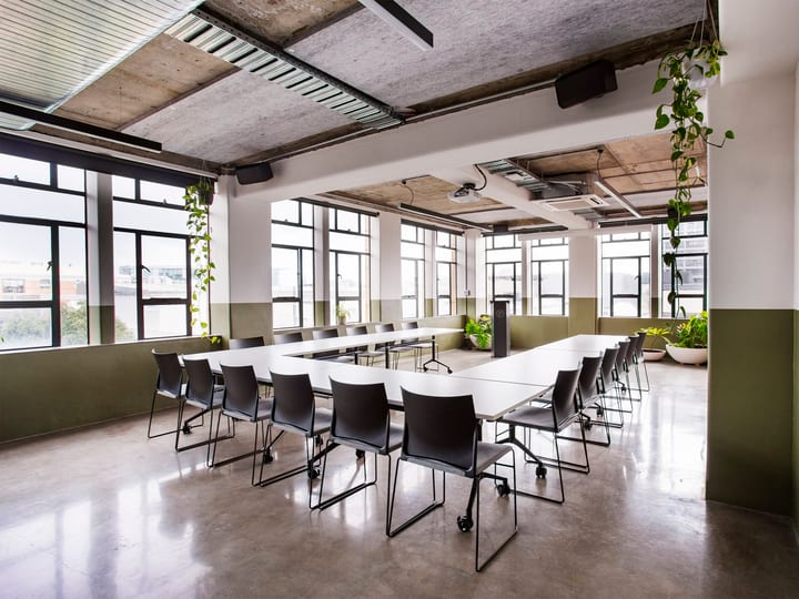 Conference room with U-shaped table layout, exposed concrete ceiling and large windows