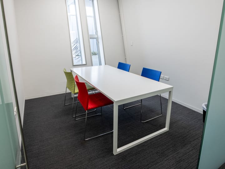 Small meeting room with white table and coloured chairs