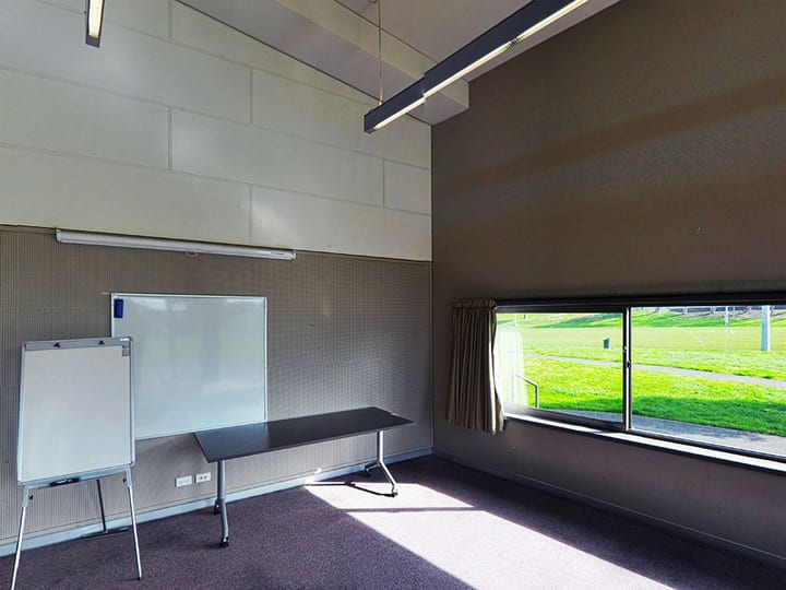Meeting room with whiteboard, flip chart, table, and window overlooking grounds