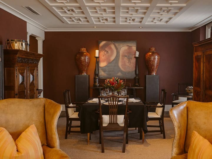 A private room with deep burgundy walls, coffered ceiling and antique furniture