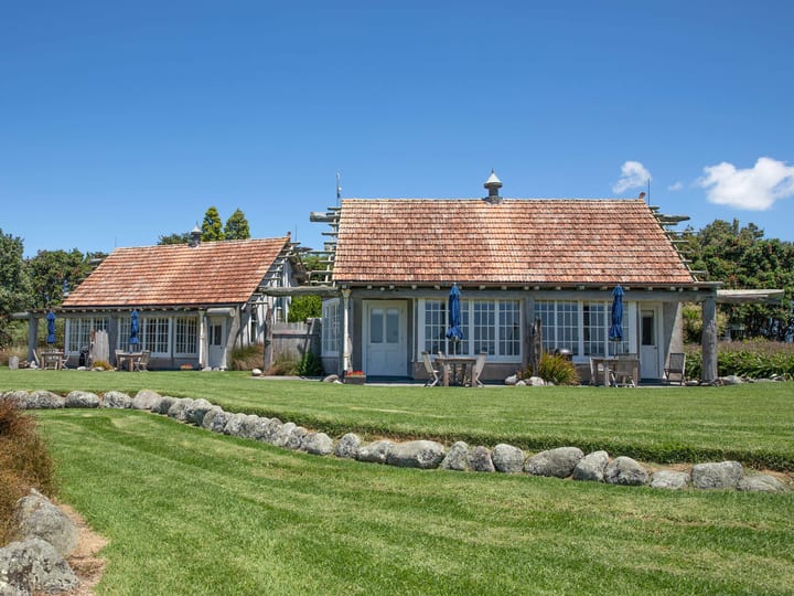 Low timber and stone villa buildings with cedar shingle roof on green lawn
