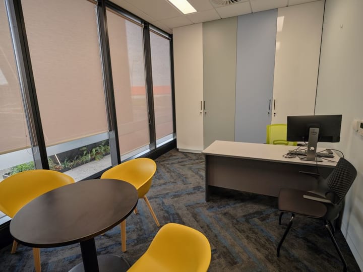 Small office room with yellow chairs, round table, and full-height glazed windows