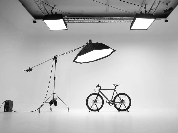 White cyclorama studio with lighting rigs and bicycle on seamless floor