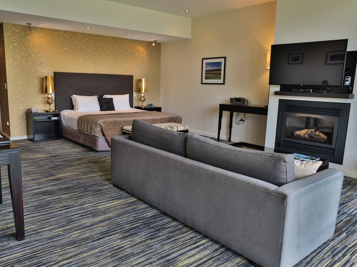 Hotel room with king bed, fireplace, sofa and mountain views through large window