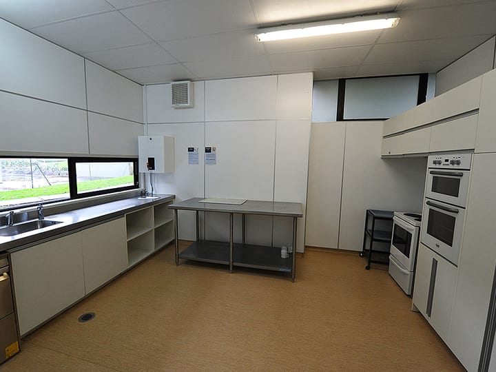 Commercial kitchen with white cabinets, stainless benches and double oven
