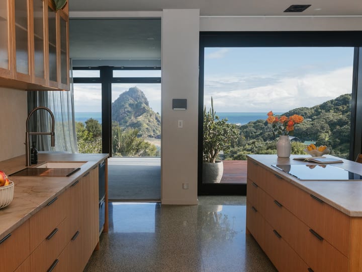 Modern kitchen with timber cabinetry, stone benchtops and large glazed doors to bush views