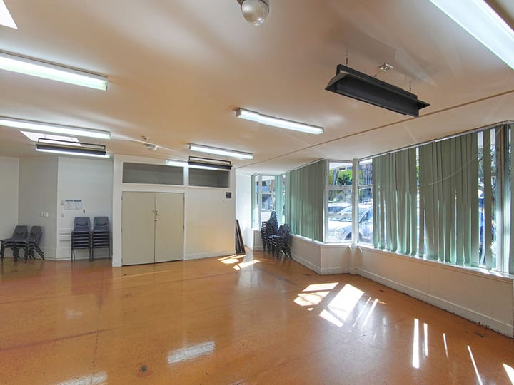 Supper room with orange vinyl floor, corner windows and green curtains