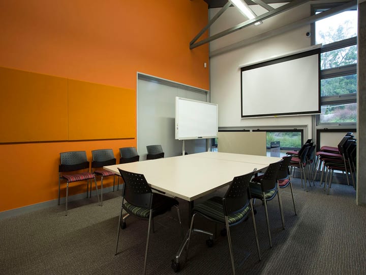Meeting room with orange accent wall, table and projection screen