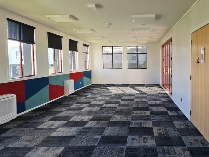 Empty room with colourful geometric mural on one wall and tiled carpet