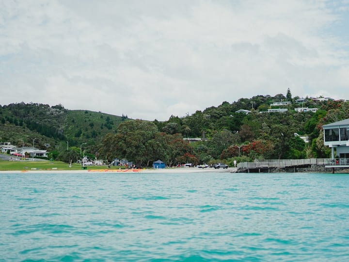 Two-storey club building on waterfront viewed from the water with hills behind