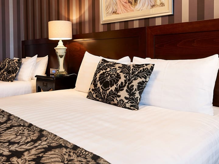 Hotel room with two double beds, striped wallpaper and framed artwork