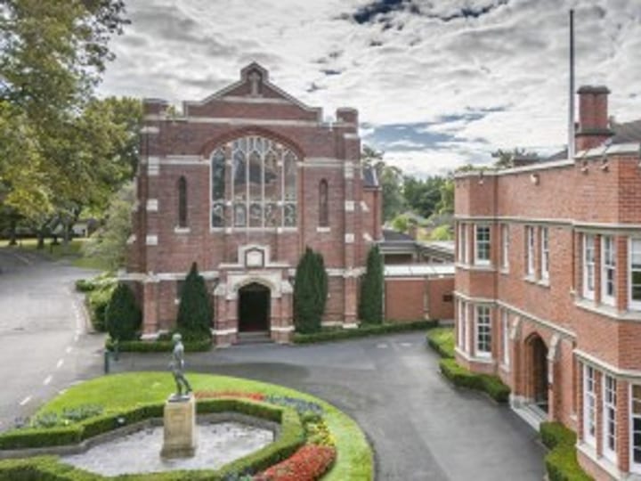 Red brick buildings with a chapel, arched entry, and landscaped grounds