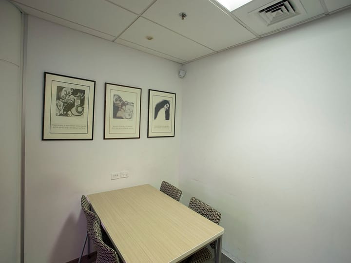 Small meeting room with timber table and four chairs, artworks on wall