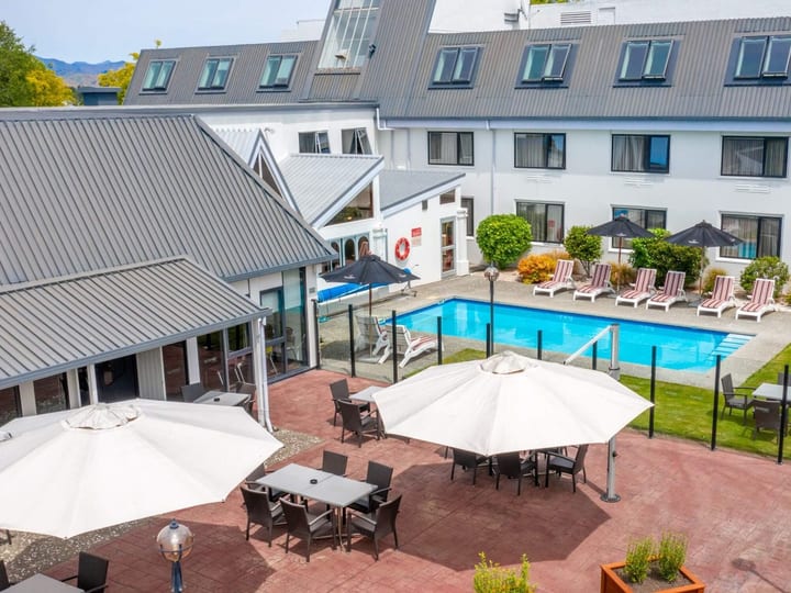 Hotel courtyard with outdoor pool, sun loungers, umbrellas and multi-storey building