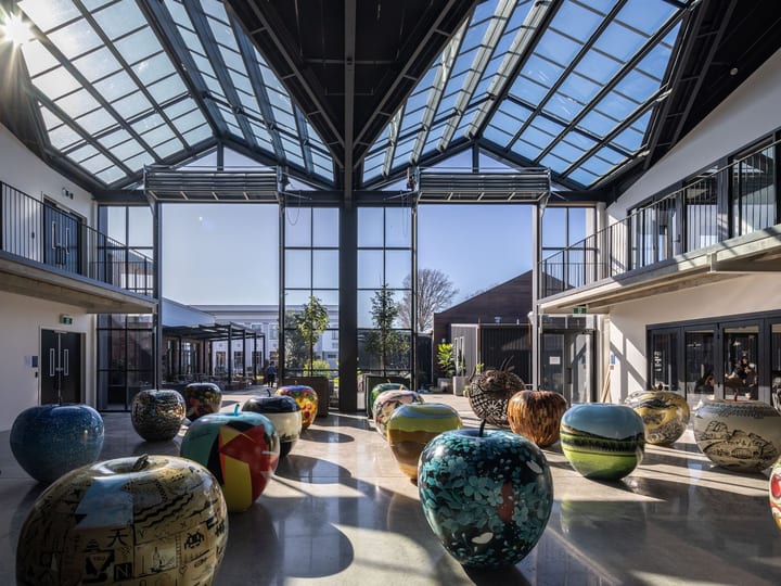 Interior atrium showing large apple sculptures, black spiral staircase and glazed roof