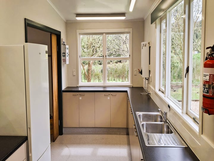 Hall kitchen with white cabinetry, dark benchtop, double sink and large windows
