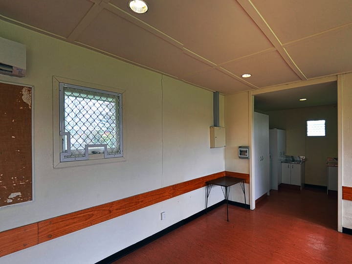 Plain supper room with timber dado rail, small table and view to adjacent kitchen