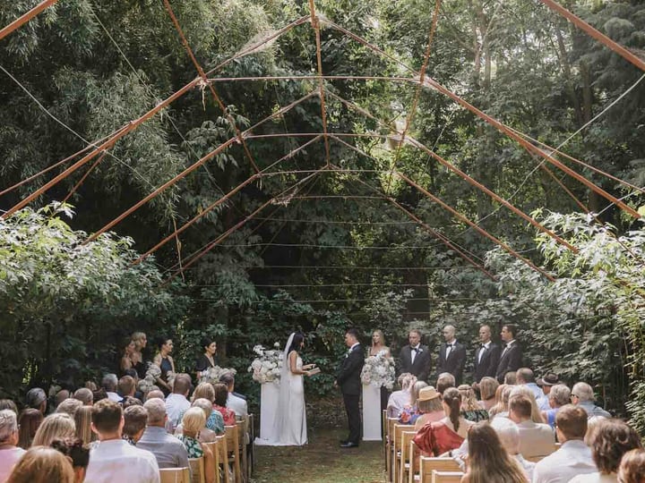 Aerial view of gravel courtyard with parasols and guests beside glass pavilion