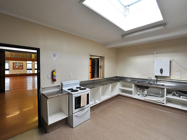Hall kitchen with stainless steel bench, sink, stove and skylight