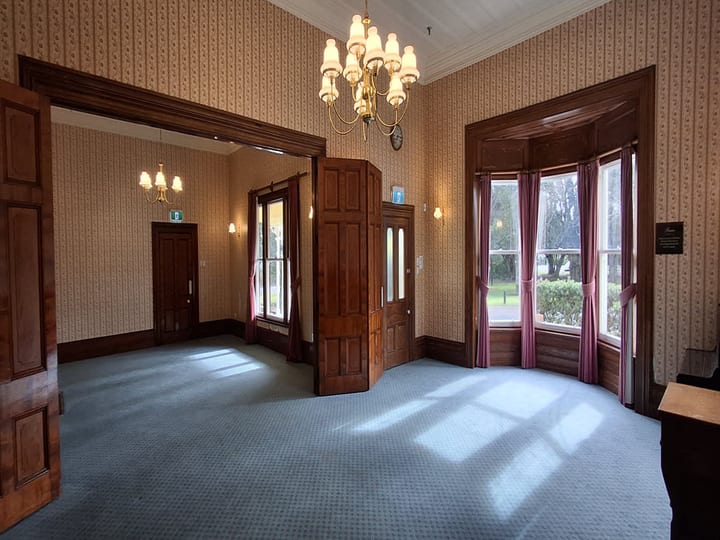 Empty Victorian room with chandelier, wallpaper, bay windows and timber doors