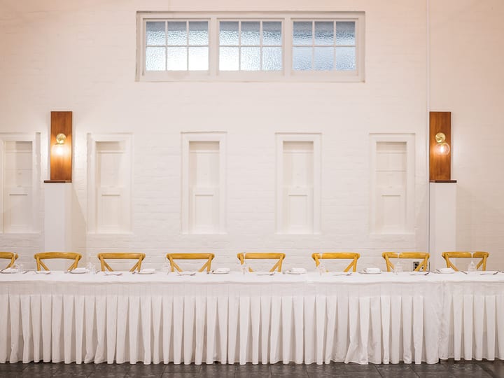 Bright white-walled function room with large windows and dining tables with guests
