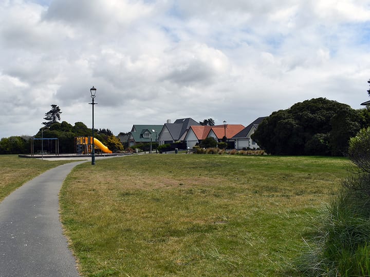 Open park with path, playground equipment and surrounding houses