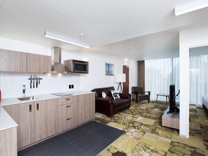 Hotel suite with open kitchen, lounge seating and patterned carpet