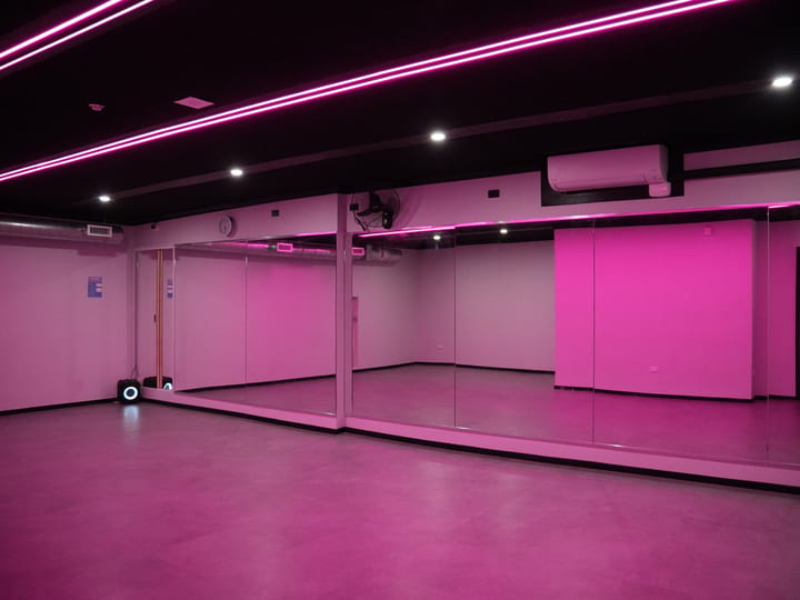 Dance studio with mirrored walls and pink neon strip lighting