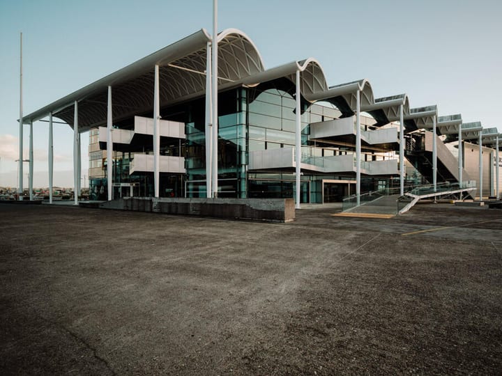 Large steel and glass event centre exterior with curved roof canopy and open forecourt