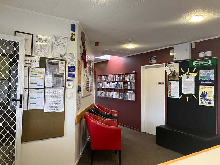Reception-style interior with red chairs, noticeboard wall and brochure rack