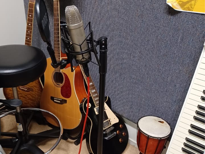 Close-up of guitars, microphone, and drum in a recording studio corner