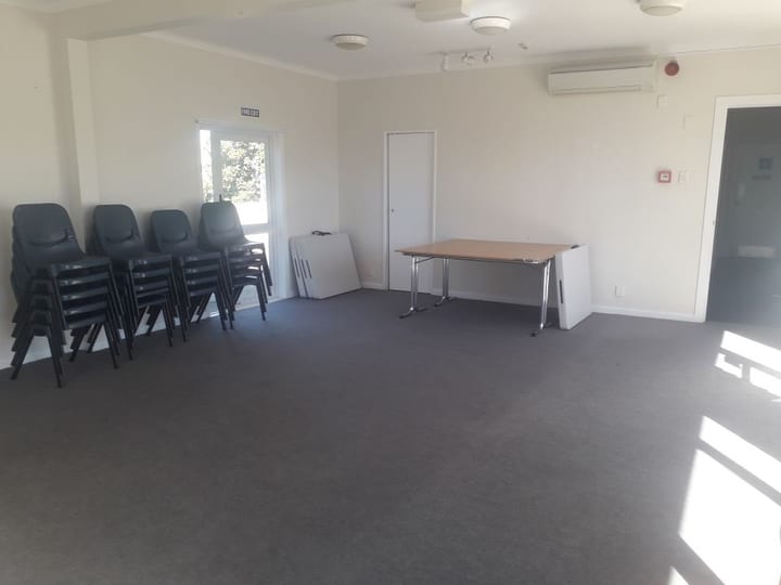 Plain room with stacked chairs, table and air conditioning unit
