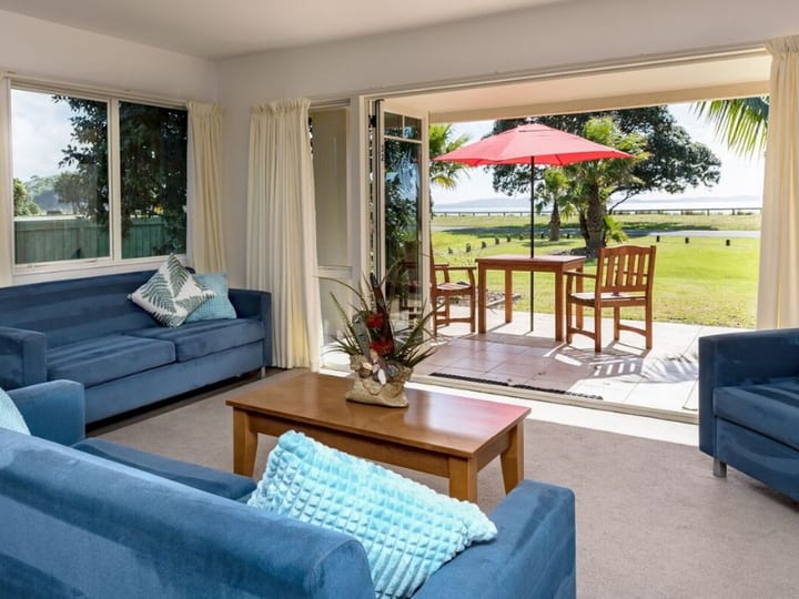 Resort unit lounge with blue sofas and open doors to outdoor patio and waterfront lawn
