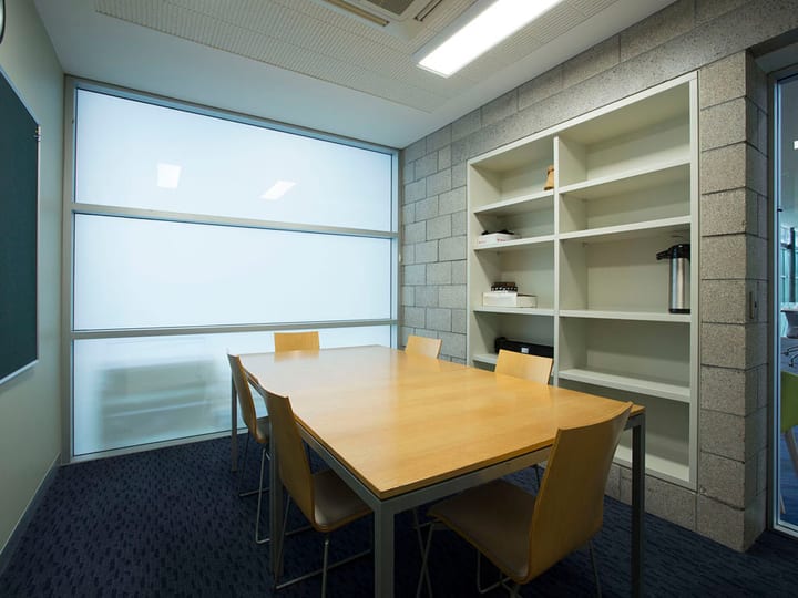 Small meeting room with table, chairs, and shelving unit