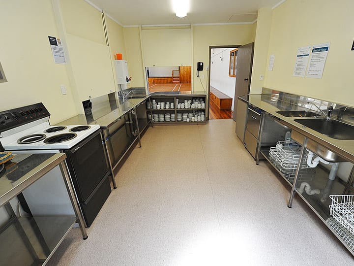 Catering kitchen with stainless benches, stove and crockery shelves