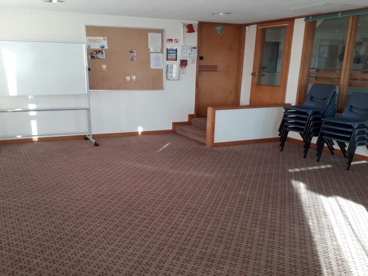 Large room with timber floor and interior windows to an adjoining room