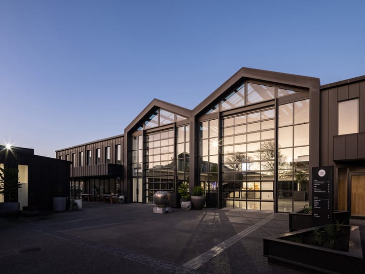 Event venue exterior at dusk, three gabled glazed facades with dark cladding
