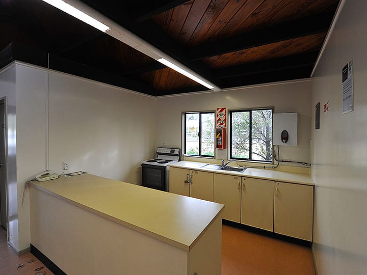 Kitchen area with bench, sink and stove under dark timber ceiling