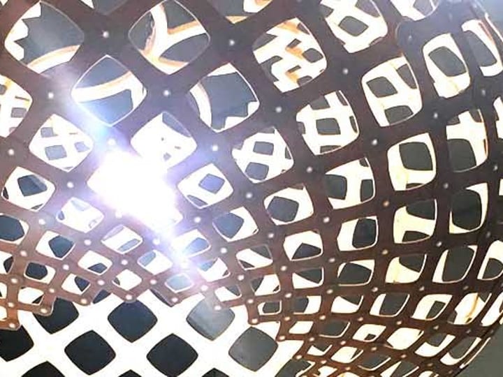Close-up of a round woven pendant light fitting against a white ceiling