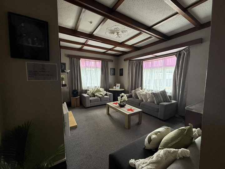 Carpeted lounge with timber coffered ceiling, sofas, and curtained windows